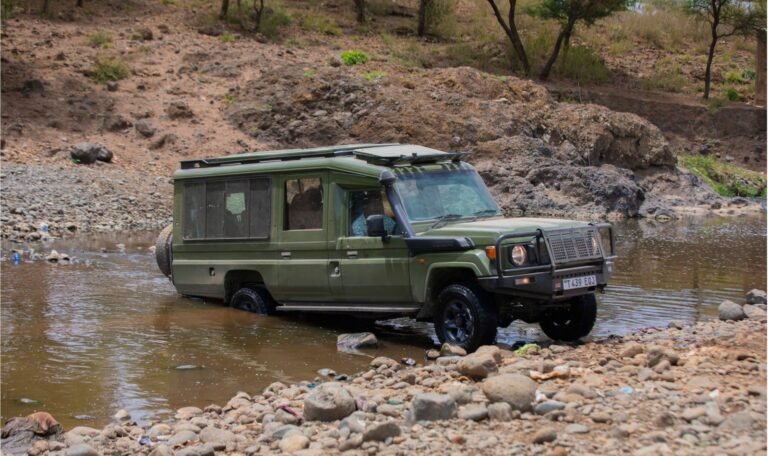 Asili Trails Land Cruiser safari vehicle crossing a shallow river