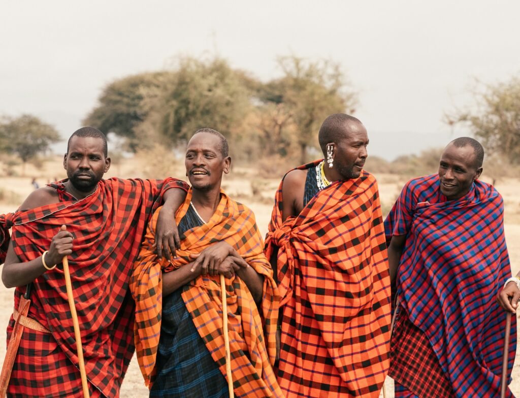 Maasai men in shukas with walking sticks on the plains