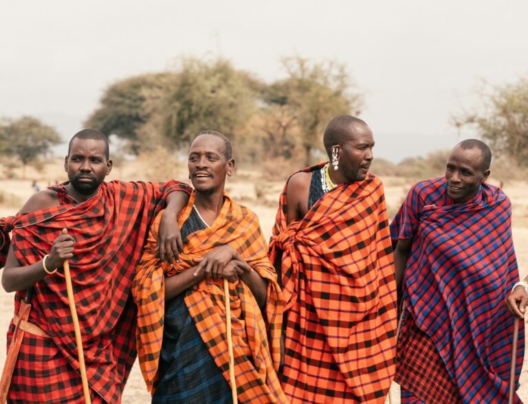 Maasai men in shukas with walking sticks on the plains