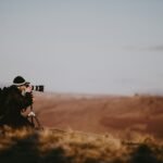 Photographer with a telephoto lens on the plains at golden hour