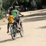 Children riding a bicycle along a village road